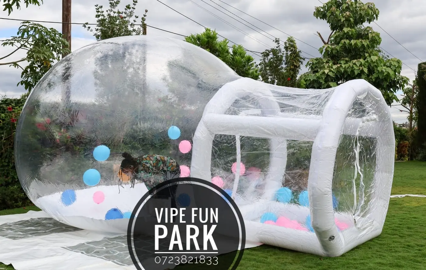 A clear inflatable bubble play zone filled with blue and pink balls on the lawn at Vipe Fun Park