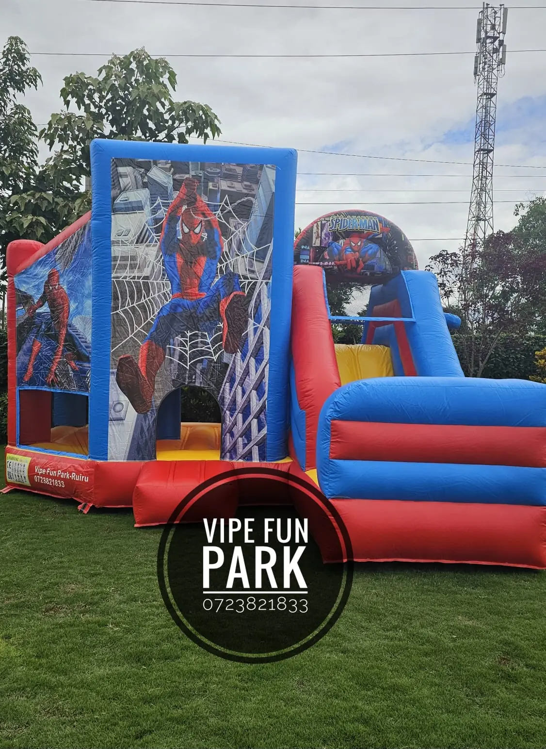 A red and blue superhero-themed bouncing castle with a climbing area and slide