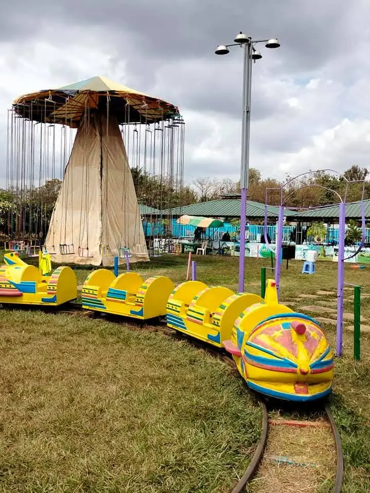 The yellow caterpillar train on its track beside the chain swing ride at Vipe Fun Park